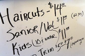 Photo of a display board for a hairdresser showing different rates.