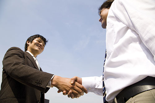 Photo shows two men in formal attire shaking hands.