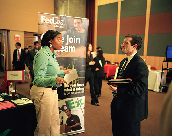 Photo shows Leslie Booth talking to a formally dressed man at a job fair.