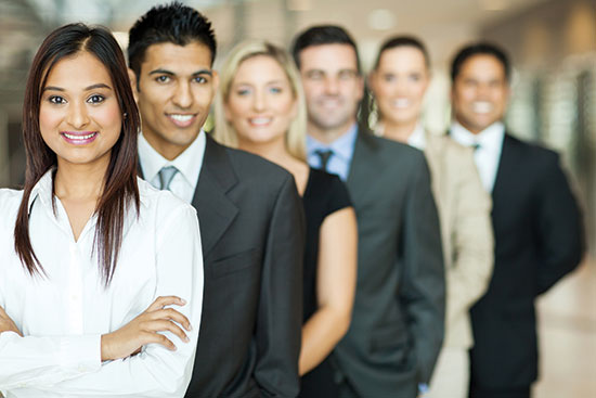 Photo shows a diverse group of men and women in business attire, smiling at the camera