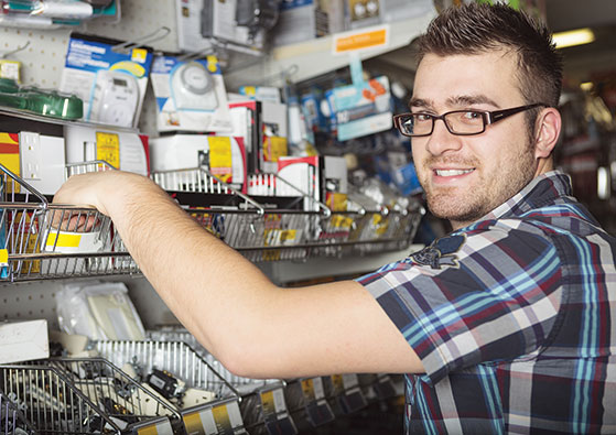 Photo shows a young man reaching into a display at a hardware store.