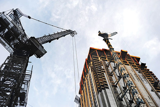 Photo shows a giant overhead crane at a construction site.