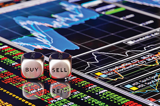 An image shows a trading screen displaying various stock data. Two dice labeled “buy” and “sell” are placed on top of the screen.