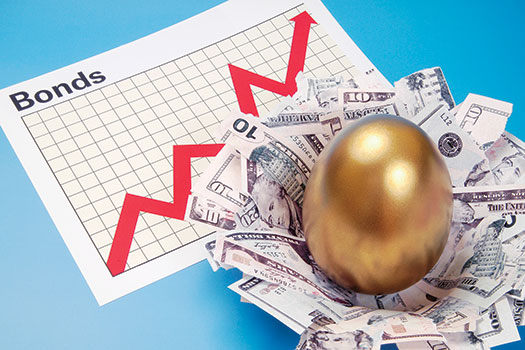 An image shows bonds with a graph on it, near to which a golden egg is placed on several currency notes.