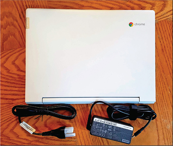 Photograph shows a Chromebook with AC adapter and power cable.