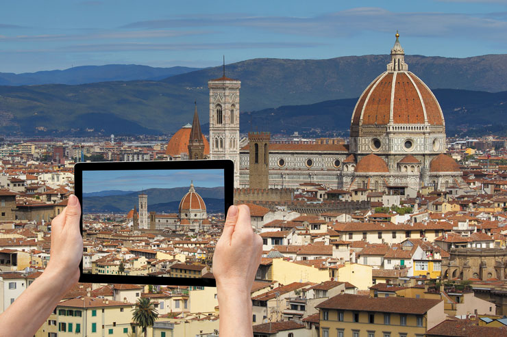 Photo of a pair of hands holding a tablet and trying to capture the scene in front in a photo.