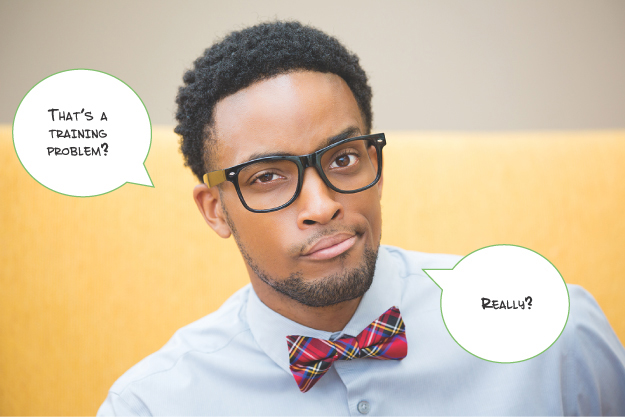 A young professional instructional designer with a skeptical look on his face. There are speech bubbles that read “That’s a training problem?” and “Really?”