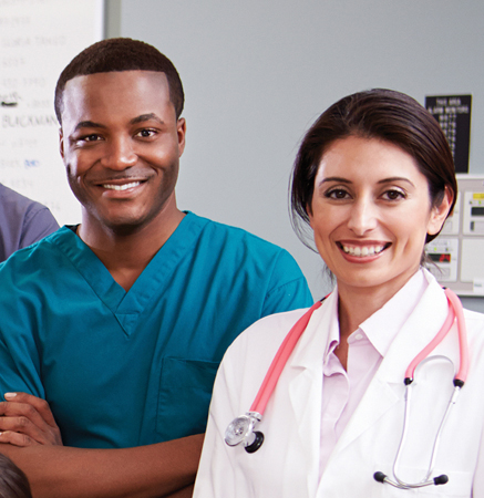 A photo of Miguel and Lisa. Miguel is a tall man wearing blue scrubs, and Lisa is wearing a lab coat and a stethoscope.