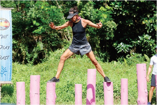 Image of  the author Janine Allis, who is crossing the wooden poles (arranged vertically).