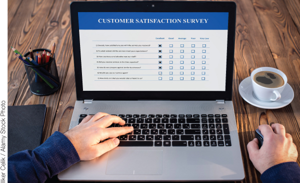 Photo illustration of a pair of hands working on a laptop whose screen displays a Customer Satisfaction Survey report.