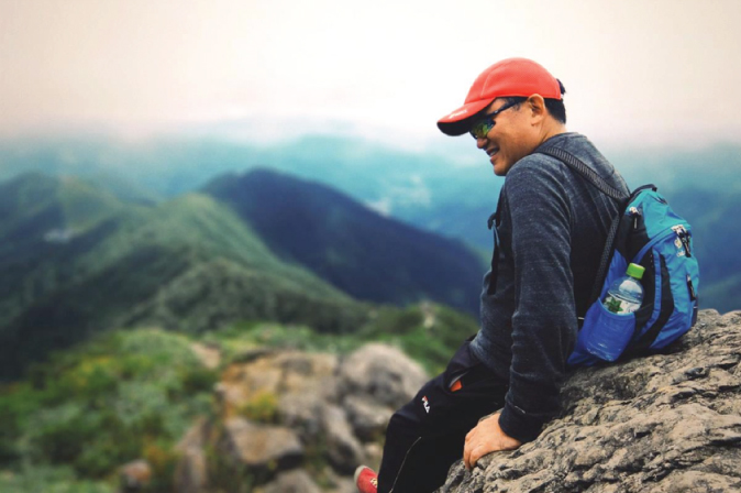 Photo illustration of a male hiker resting against a rock.