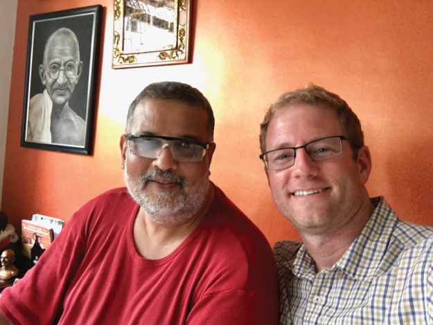 Photograph of Tushar Gandhi, Mahatma Gandhi’s great-grandson, and the author with the photograph of Mahatma Gandhi in the background.