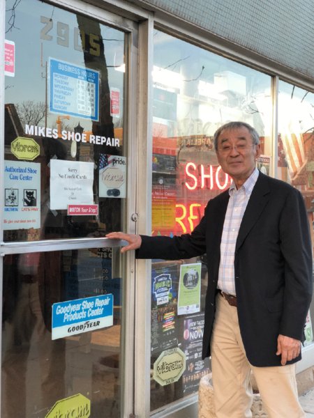 Image of the shoe repairman, Mike, who is posing outside of his shop. 