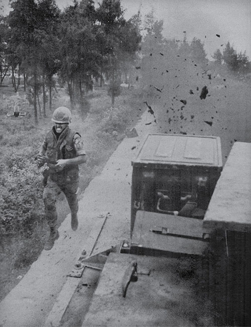 Image of an ARVN solider with a twisted expression on his face, as a mortar round hits near him on the crowded road outside Dongha. 