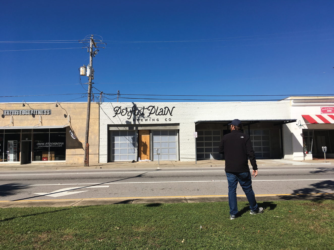 Photograph of a man in front of the same old shop being converted into a craft brewery, supervising the work in progress.