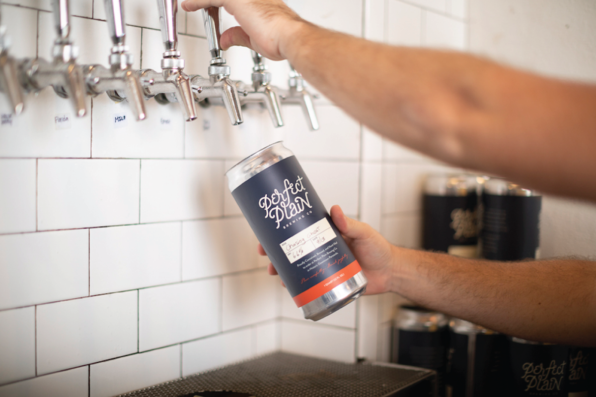 Photograph depicting the taproom of a brewery with a person about to fill his can of drink.