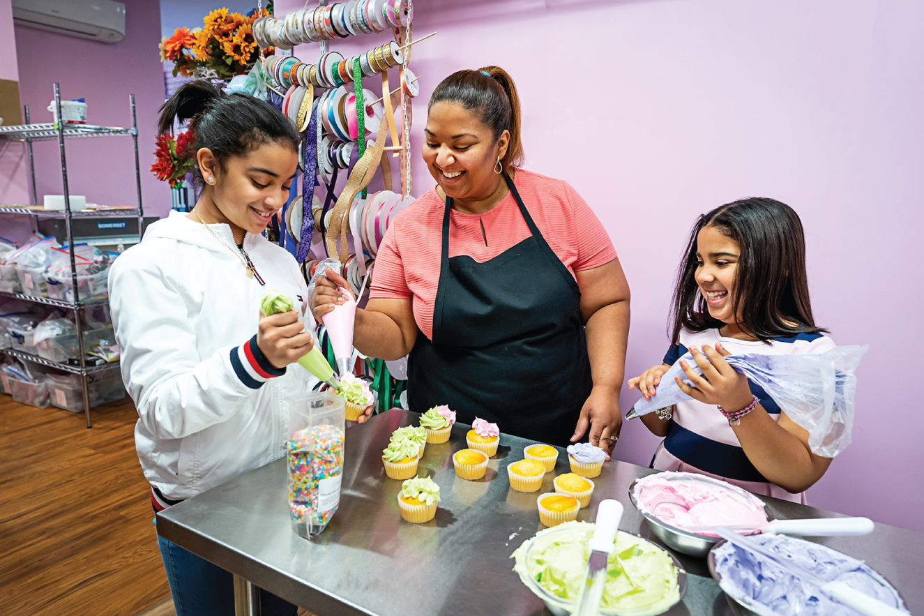 Photograph of Denaris and her daughters Grace (left) and Rebecca decorate cupcakes. 