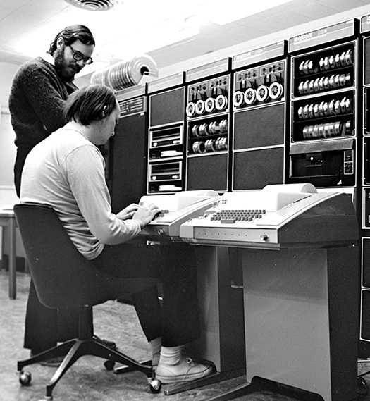 A photograph of two Unix developers using a teletype is shown.