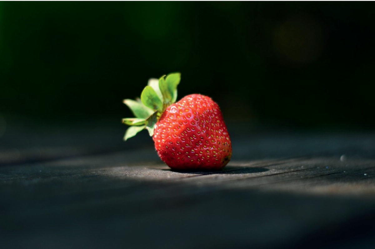 A photograph of a strawberry focused with a bright light.