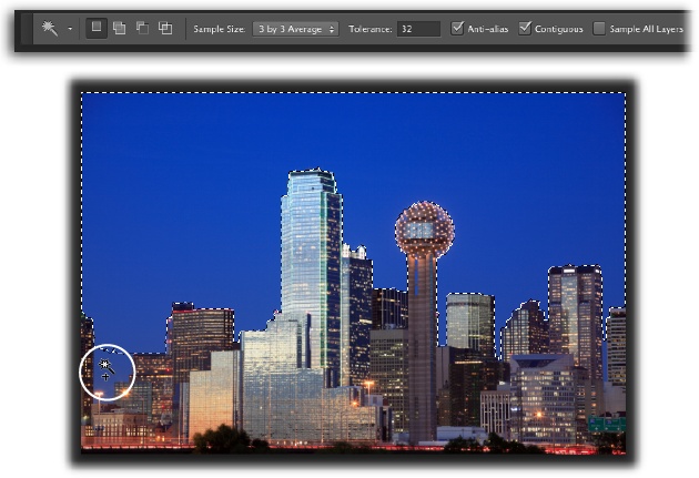 With its tolerance set to 32, the Magic Wand did a good job of selecting the sky behind downtown Dallas.You’ve got several ways to select the spots it missed, like the area circled at the bottom left: You can add to the selection by pressing the Shift key as you click in that area, increase the Tolerance setting in the Options bar and then click the sky again to create a brand-new selection, or skip to page 156 to learn how to expand the selection with the Grow and Similar commands.Give this selection technique a shot by downloading the practice file Dallas.jpg from this book’s Missing CD page at www.missingmanuals.com/cds.