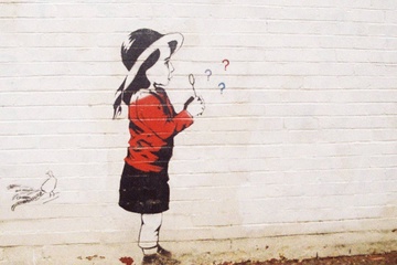 Painting on wall of girl blowing question marks.
